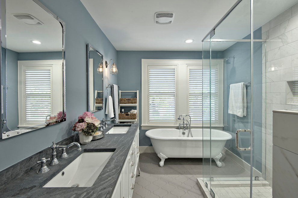 Bild på ett amerikanskt en-suite badrum, med vita skåp, ett badkar med tassar, en hörndusch, en toalettstol med hel cisternkåpa, grå kakel, stenkakel, blå väggar, klinkergolv i porslin, ett undermonterad handfat och bänkskiva i täljsten