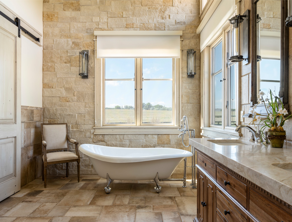 This is an example of a country bathroom in Denver with dark wood cabinets, a claw-foot bath, brown tiles, white walls, a submerged sink, brown floors, beige worktops and flat-panel cabinets.