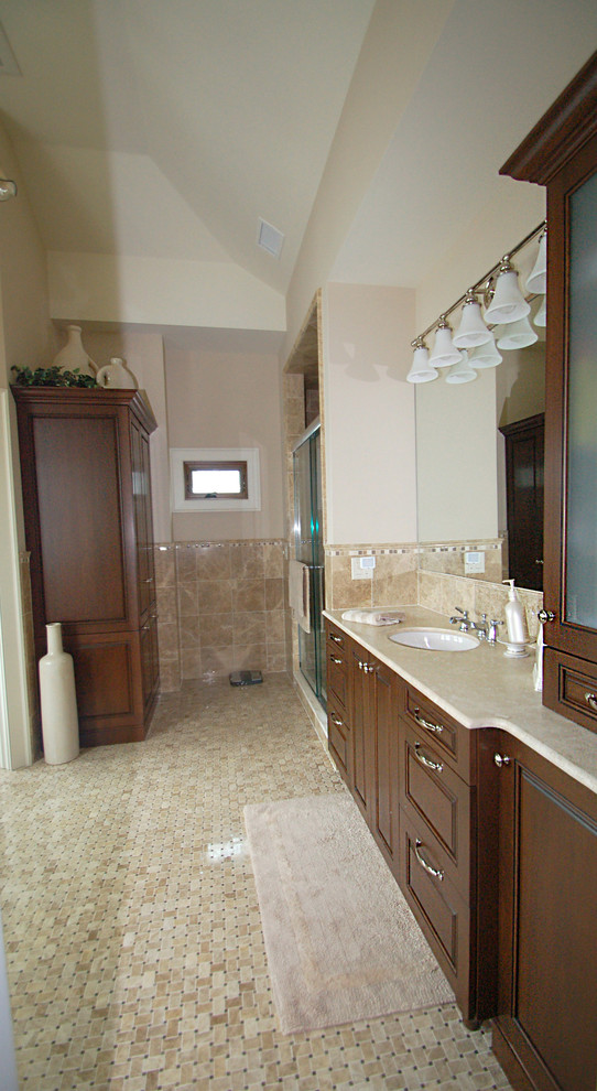 Идея дизайна: главная ванная комната среднего размера в классическом стиле с фасадами с выступающей филенкой, темными деревянными фасадами, ванной в нише, душем в нише, унитазом-моноблоком, бежевой плиткой, каменной плиткой, бежевыми стенами, полом из мозаичной плитки, врезной раковиной и мраморной столешницей