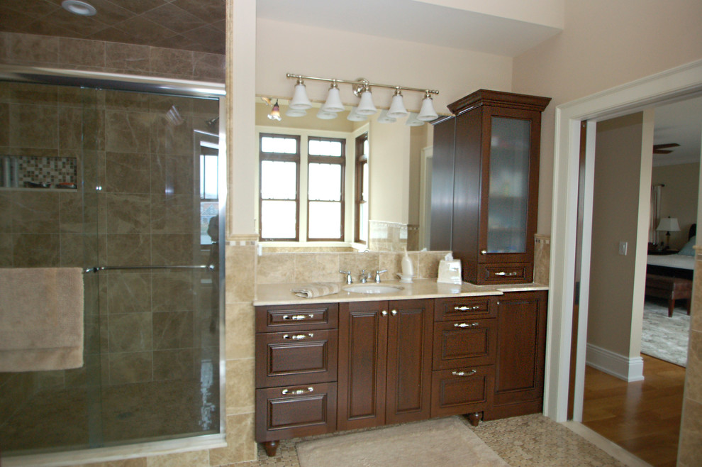 Mid-sized elegant master beige tile and stone tile mosaic tile floor bathroom photo in Newark with raised-panel cabinets, dark wood cabinets, a one-piece toilet, beige walls, an undermount sink and marble countertops