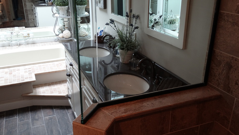 Exemple d'une salle de bain principale chic en bois vieilli de taille moyenne avec un lavabo encastré, un placard avec porte à panneau surélevé, une baignoire posée, une douche d'angle, un carrelage beige et parquet foncé.