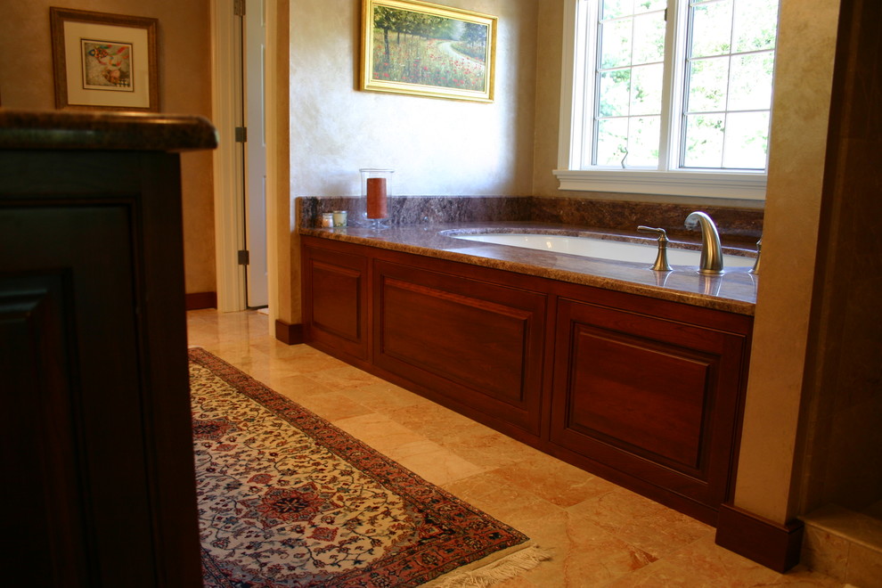 Idée de décoration pour une salle de bain principale tradition en bois brun avec un lavabo encastré, un placard avec porte à panneau encastré et une baignoire encastrée.