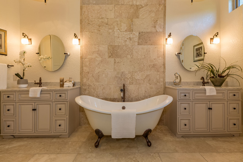Immagine di una stanza da bagno tradizionale con ante con bugna sagomata, ante beige, vasca con piedi a zampa di leone, piastrelle beige, pareti beige, lavabo sottopiano, pavimento beige e top beige