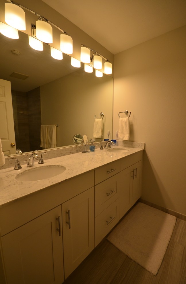 Inredning av ett modernt litet badrum med dusch, med ett undermonterad handfat, skåp i shakerstil, vita skåp, marmorbänkskiva, ett badkar med tassar, en dusch i en alkov, en toalettstol med hel cisternkåpa, grå kakel, porslinskakel, grå väggar och klinkergolv i porslin