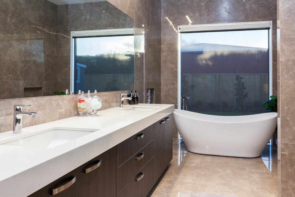 Cette image montre une grande salle de bain principale minimaliste en bois foncé avec une baignoire indépendante, un carrelage marron, un carrelage de pierre, un mur marron, une cabine de douche à porte battante et un plan de toilette blanc.