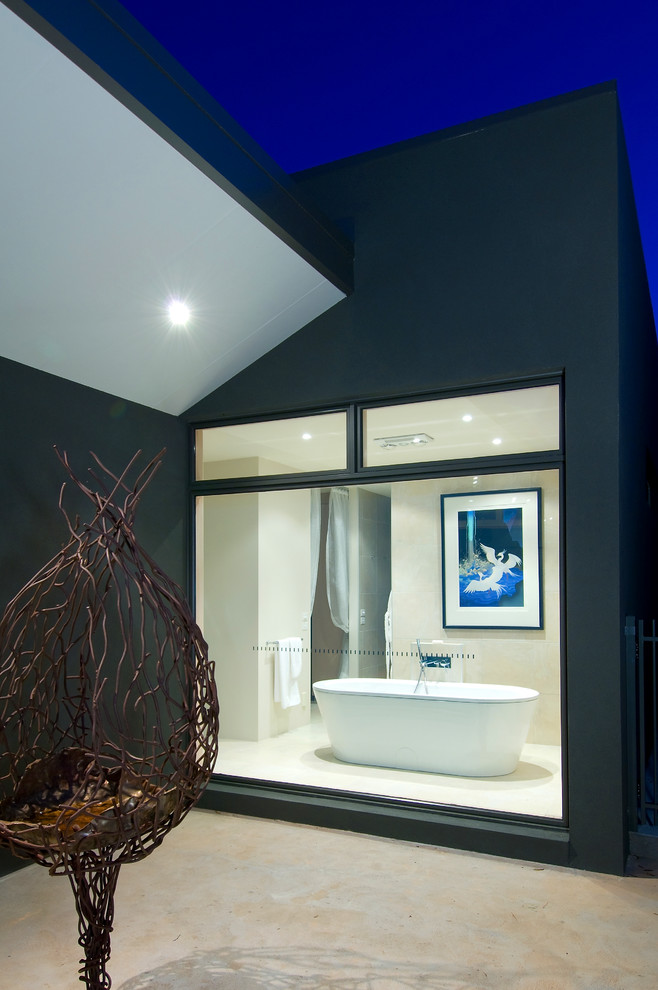 Exemple d'une salle de bain tendance avec une baignoire indépendante, un carrelage beige, un carrelage de pierre et un mur beige.