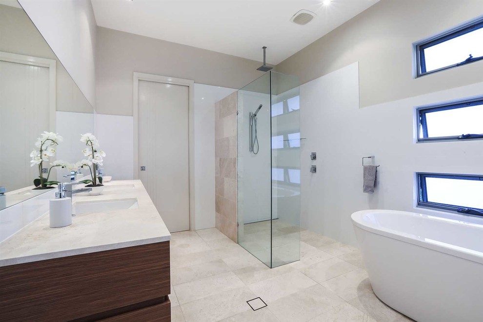 Photo of a large modern ensuite bathroom in Gold Coast - Tweed with medium wood cabinets, a freestanding bath, a walk-in shower, white tiles, ceramic tiles, white walls, ceramic flooring, a built-in sink, white floors, an open shower and white worktops.