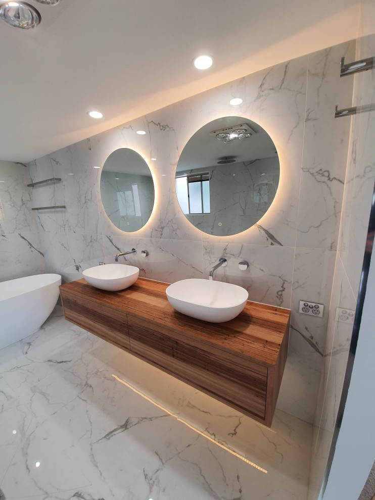 Стильный дизайн: большая главная ванная комната в стиле модернизм с светлыми деревянными фасадами, двойным душем, черно-белой плиткой, керамической плиткой, полом из керамической плитки, открытым душем, тумбой под две раковины и подвесной тумбой - последний тренд