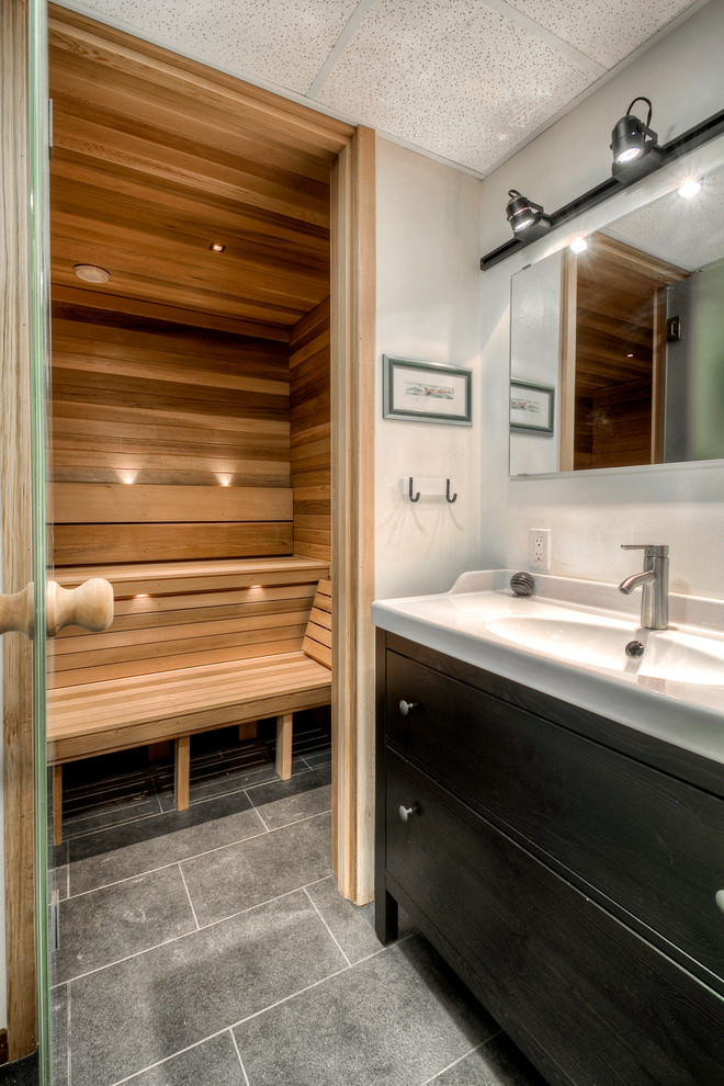 Cette image montre un sauna design de taille moyenne avec un placard à porte plane, des portes de placard noires, un carrelage blanc, un mur blanc, un sol en carrelage de porcelaine, un lavabo intégré, un plan de toilette en surface solide et un sol gris.