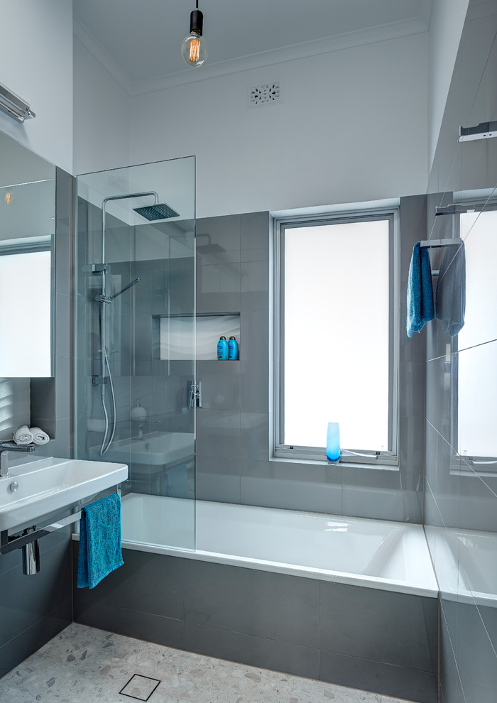 Ejemplo de cuarto de baño principal moderno pequeño con lavabo suspendido, bañera encastrada, ducha abierta, sanitario de pared, baldosas y/o azulejos grises, paredes grises y suelo de baldosas de porcelana