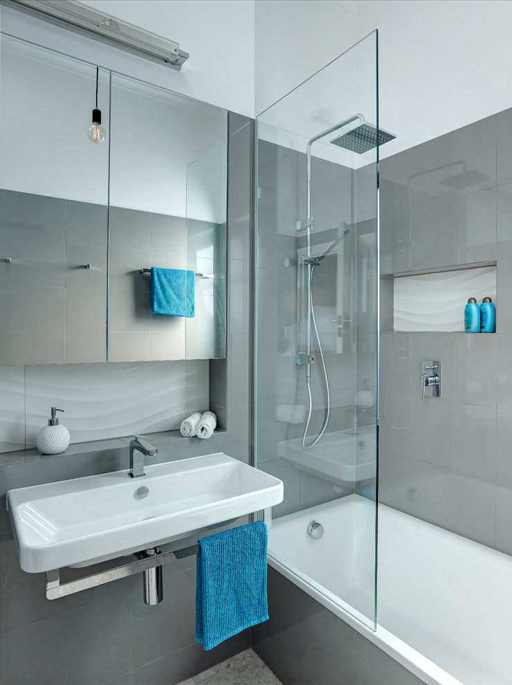 Imagen de cuarto de baño principal minimalista pequeño con lavabo suspendido, bañera encastrada, ducha abierta, sanitario de pared, baldosas y/o azulejos grises, paredes grises y suelo de baldosas de porcelana