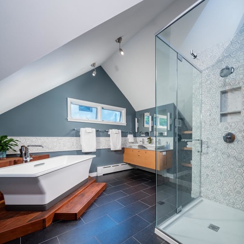 Inspiration för mellanstora moderna en-suite badrum, med släta luckor, skåp i ljust trä, ett fristående badkar, en kantlös dusch, blå väggar, ett fristående handfat och svart golv