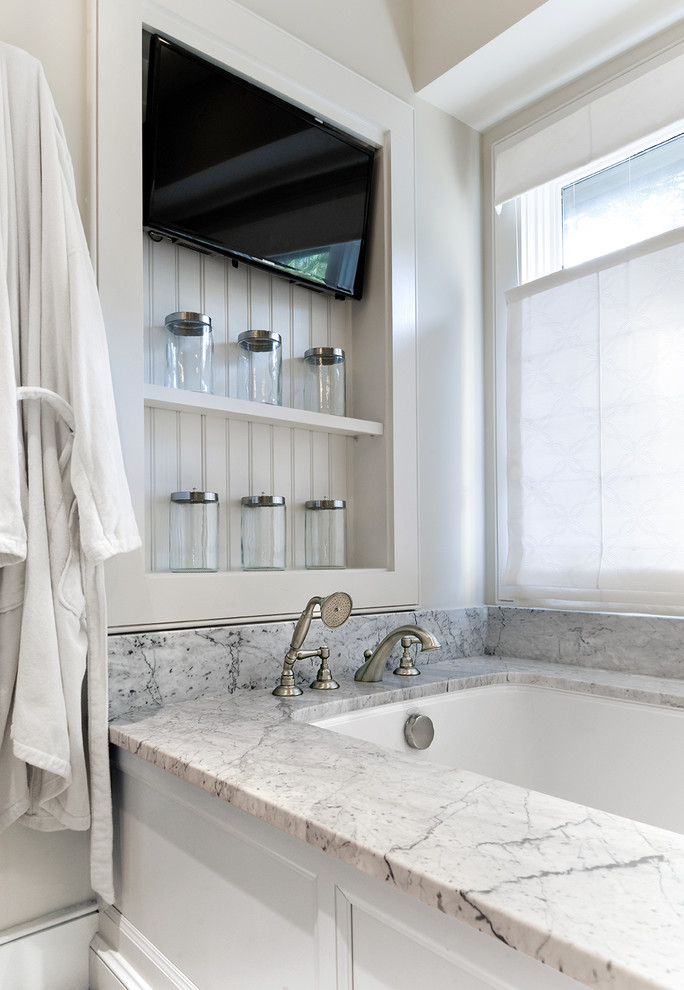 Diseño de cuarto de baño principal, tradicional renovado, grande, con lavabo bajoencimera, armarios con paneles lisos, puertas de armario blancas, encimera de mármol, bañera encastrada sin remate, sanitario de dos piezas, baldosas y/o azulejos blancos, baldosas y/o azulejos de cerámica, paredes blancas y suelo de mármol