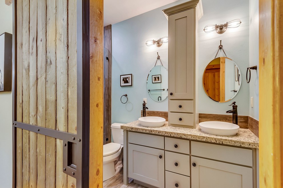 Example of a mid-sized beach style 3/4 beige tile and porcelain tile porcelain tile and beige floor alcove shower design in Other with shaker cabinets, white cabinets, blue walls, a vessel sink, granite countertops, a hinged shower door and a two-piece toilet