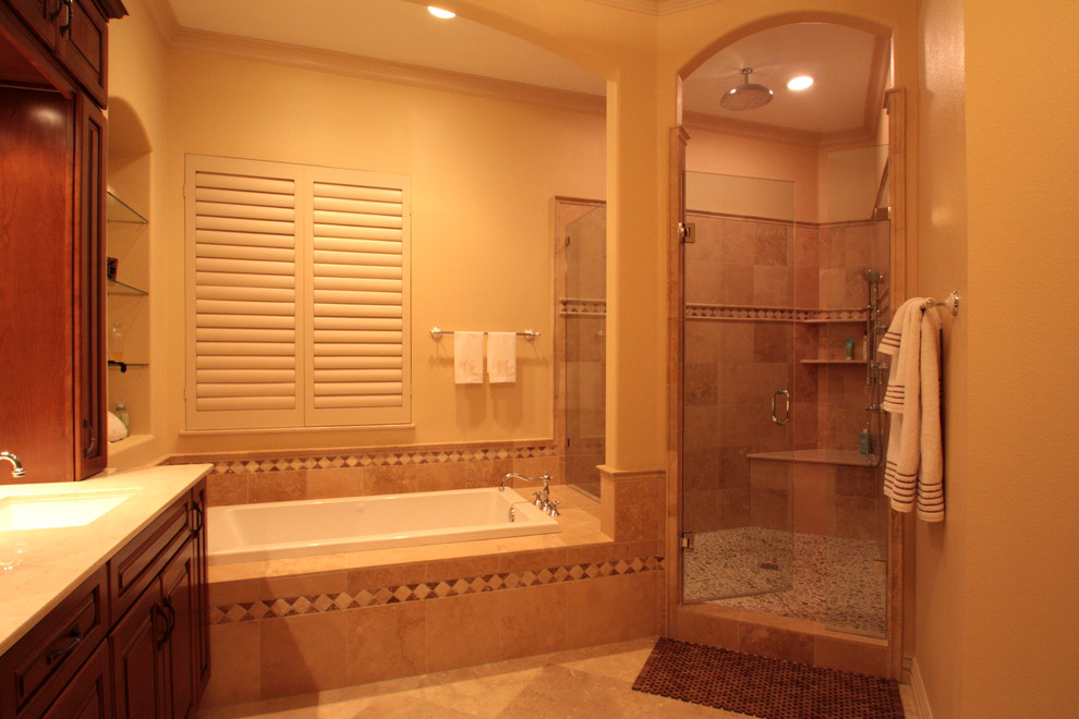 Immagine di una stanza da bagno padronale tradizionale con lavabo sottopiano, ante a filo, ante in legno bruno, vasca da incasso, doccia alcova, piastrelle beige, piastrelle di ciottoli, pareti beige e pavimento in travertino