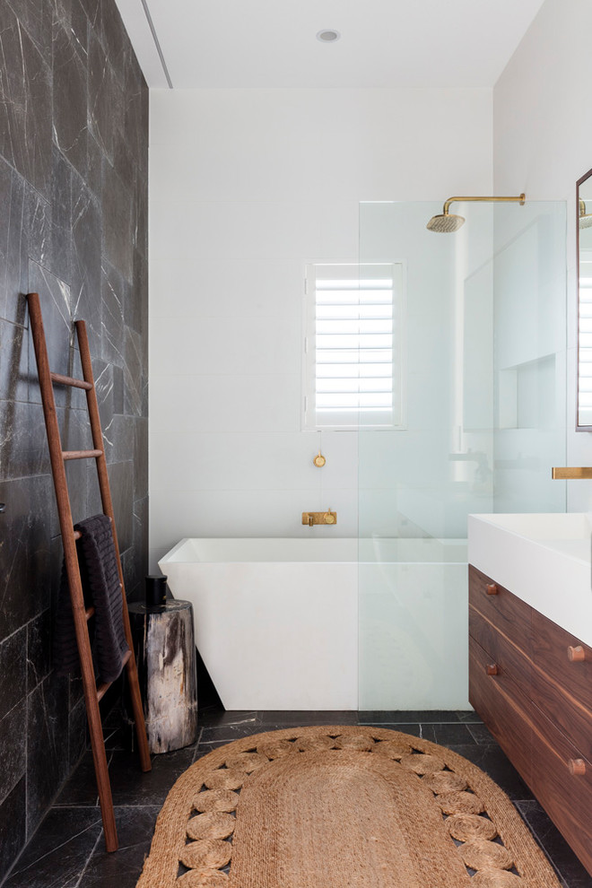 Inspiration for a mid-sized contemporary master white tile and ceramic tile limestone floor and gray floor bathroom remodel in Sydney with furniture-like cabinets, dark wood cabinets, a wall-mount toilet, gray walls, an integrated sink and solid surface countertops