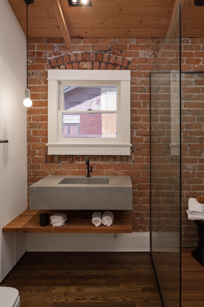 Foto på ett industriellt badrum, med ett väggmonterat handfat, en kantlös dusch, vita väggar och mörkt trägolv