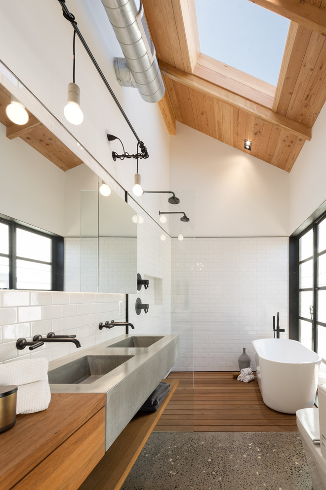 Idéer för ett industriellt brun badrum, med träbänkskiva, vit kakel, tunnelbanekakel, ett fristående badkar, ett integrerad handfat, vita väggar, mellanmörkt trägolv, släta luckor, skåp i mellenmörkt trä, en öppen dusch och med dusch som är öppen