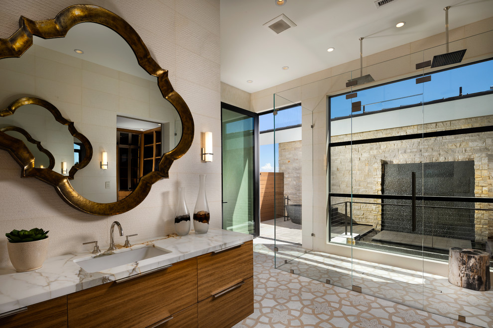 Photo of a large contemporary ensuite bathroom in Phoenix with flat-panel cabinets, medium wood cabinets, a freestanding bath, a double shower, white tiles, stone tiles, white walls, porcelain flooring, a submerged sink, engineered stone worktops, white floors, a hinged door and white worktops.