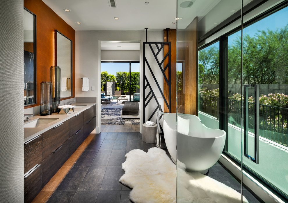 Large contemporary ensuite bathroom in Phoenix with flat-panel cabinets, engineered stone worktops, brown floors, grey worktops, a freestanding bath, a submerged sink, dark wood cabinets and grey walls.