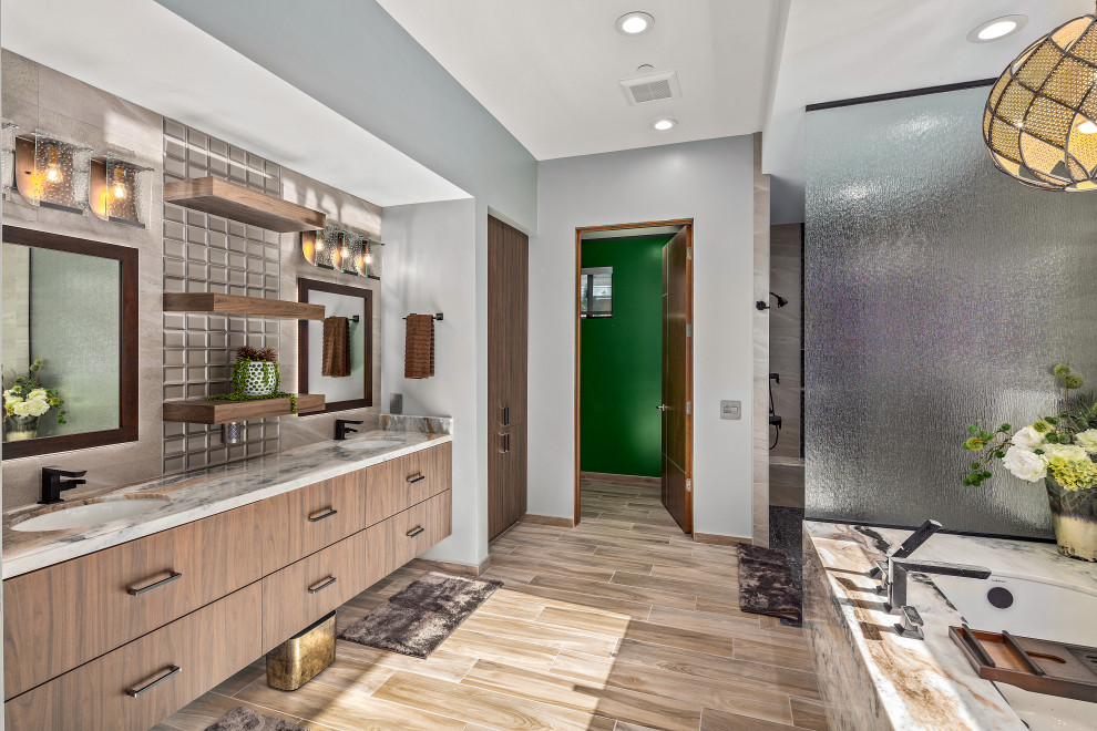 Inspiration för moderna grått badrum, med släta luckor, skåp i mörkt trä, ett undermonterat badkar, grå kakel, grå väggar, ett undermonterad handfat och brunt golv