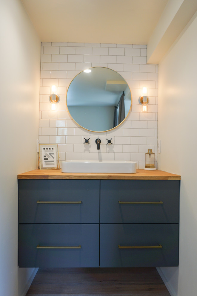 На фото: ванная комната в скандинавском стиле с плоскими фасадами, синими фасадами, душем в нише, белой плиткой, цементной плиткой, светлым паркетным полом, настольной раковиной, столешницей из дерева, бежевым полом и душем с распашными дверями