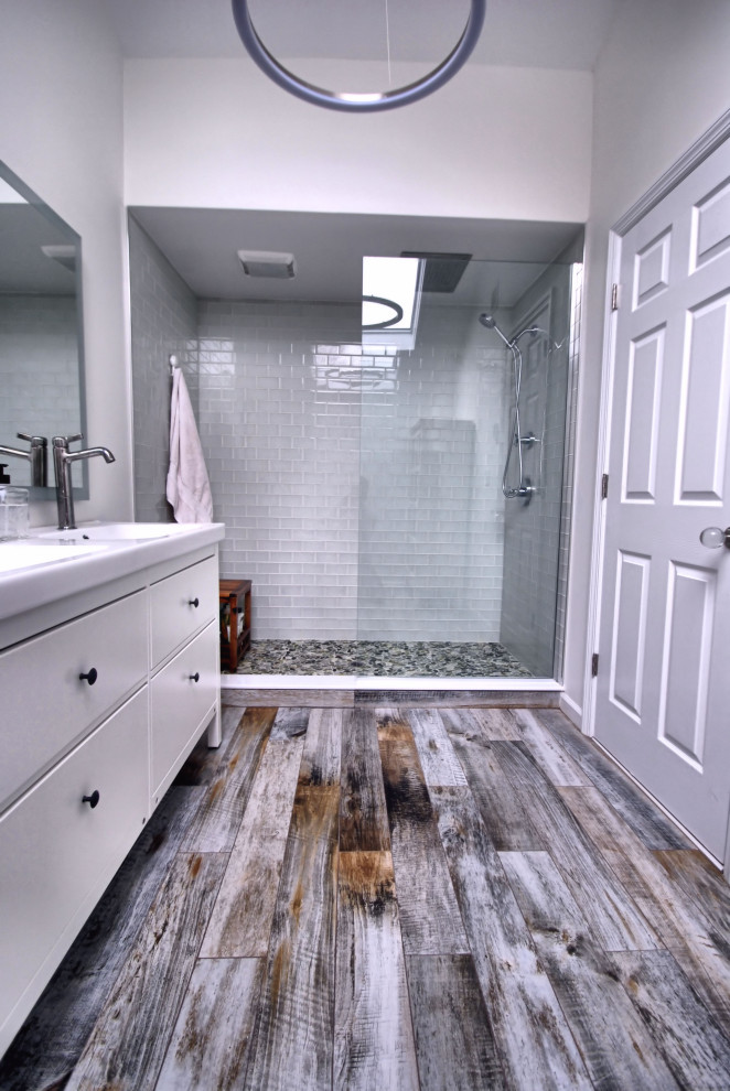 Example of a mid-sized mountain style master green tile and glass tile porcelain tile and multicolored floor bathroom design in New York with flat-panel cabinets, white cabinets, a two-piece toilet, gray walls, an integrated sink, quartz countertops and white countertops