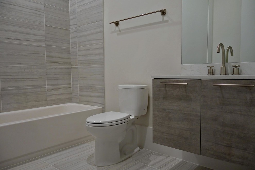 Bathroom - mid-sized contemporary master porcelain tile porcelain tile bathroom idea in Houston with flat-panel cabinets, gray cabinets, a two-piece toilet, white walls, an undermount sink and marble countertops