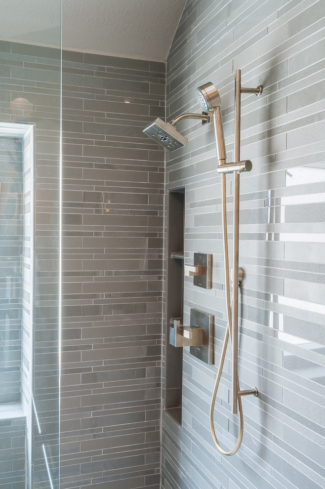 Immagine di una stanza da bagno padronale minimalista di medie dimensioni con lavabo sottopiano, consolle stile comò, ante in legno scuro, top in superficie solida, WC monopezzo, piastrelle grigie, pareti grigie e pavimento in gres porcellanato