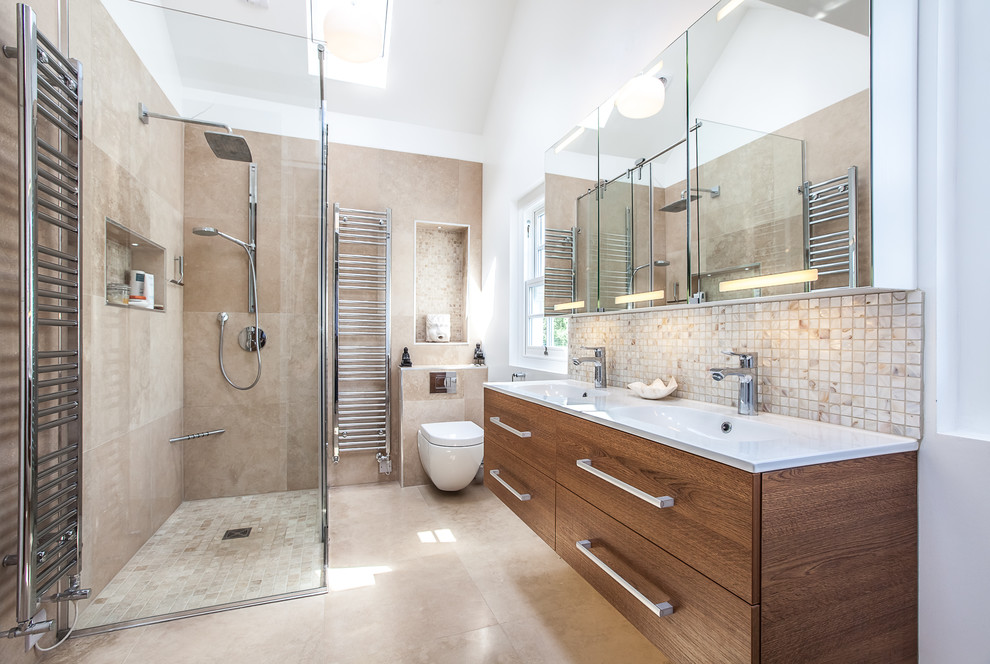 Immagine di una stanza da bagno con doccia contemporanea con ante lisce, ante in legno bruno, doccia ad angolo, WC sospeso, piastrelle beige, pareti beige, lavabo integrato, pavimento beige e top bianco