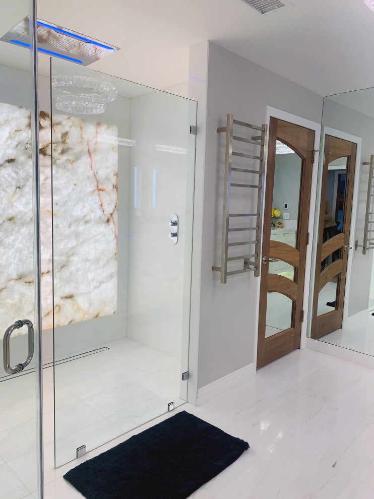 Klassisk inredning av ett stort flerfärgad flerfärgat en-suite badrum, med luckor med glaspanel, vita skåp, en kantlös dusch, en vägghängd toalettstol, grå kakel, marmorkakel, marmorgolv, ett undermonterad handfat, marmorbänkskiva, vitt golv och dusch med gångjärnsdörr
