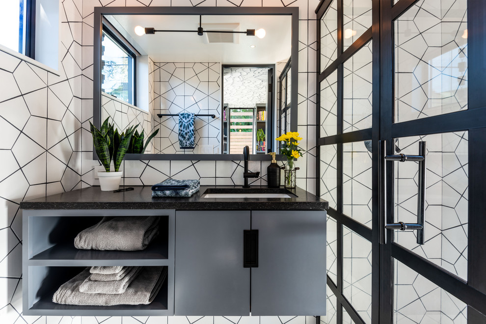 Example of a small trendy 3/4 white tile and ceramic tile alcove shower design in Seattle with flat-panel cabinets, an undermount sink, solid surface countertops, a hinged shower door, black countertops and gray cabinets