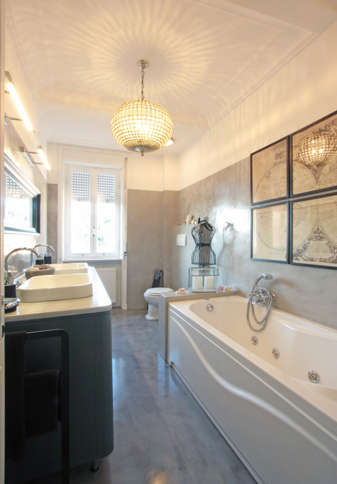 Immagine di una stanza da bagno chic con vasca freestanding, WC monopezzo, piastrelle in gres porcellanato, pareti grigie, pavimento in gres porcellanato e lavabo da incasso