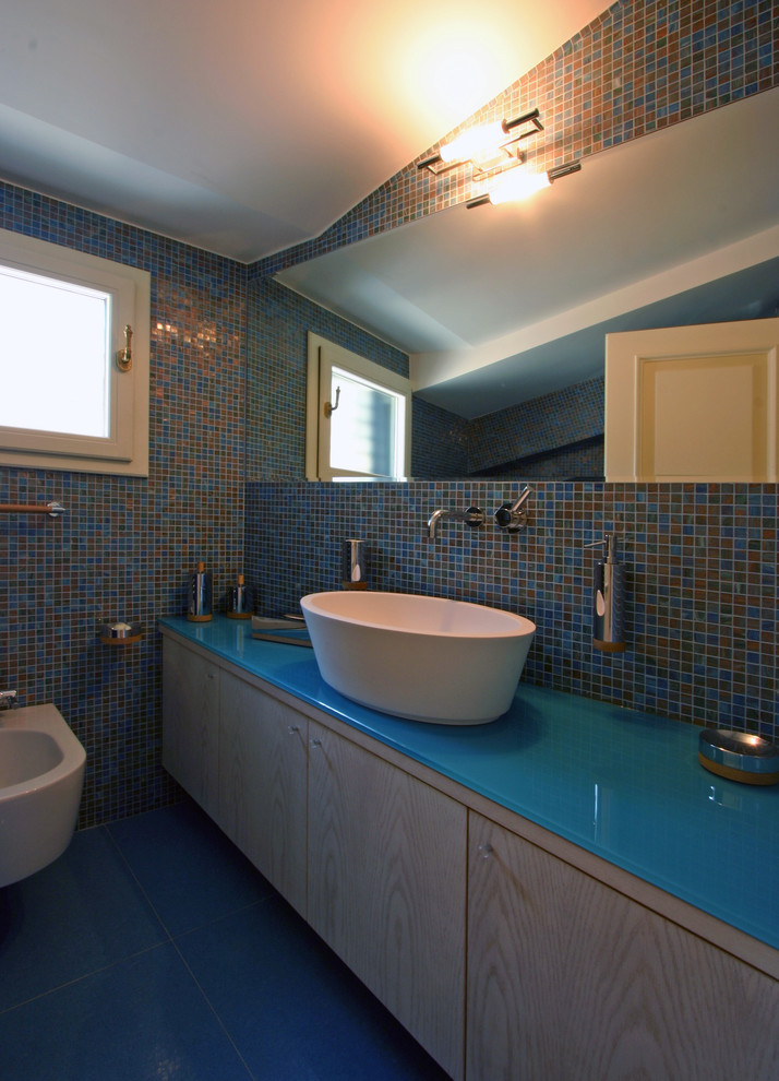 Esempio di una stanza da bagno per bambini contemporanea di medie dimensioni con lavabo da incasso, consolle stile comò, ante in legno chiaro, top in vetro, doccia alcova, WC sospeso, piastrelle blu, piastrelle a mosaico, pareti blu e pavimento con piastrelle in ceramica