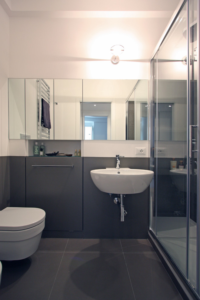 Modern inredning av ett litet badrum med dusch, med ett konsol handfat, en dusch i en alkov, en vägghängd toalettstol, grå kakel, keramikplattor, grå väggar och klinkergolv i keramik