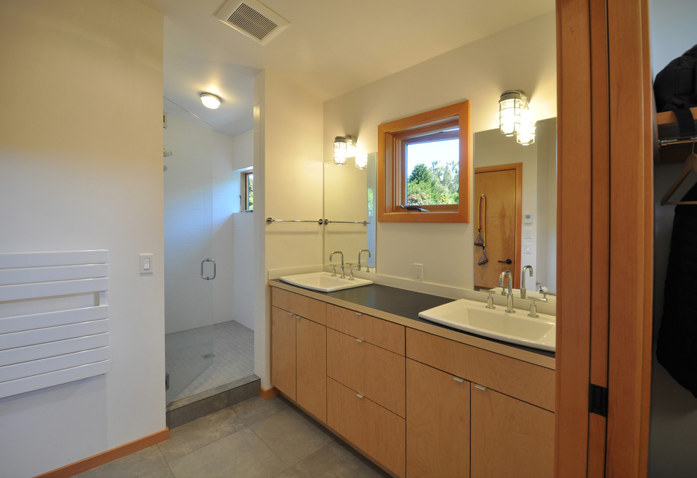 Design ideas for a small contemporary bathroom in Seattle with a built-in sink, flat-panel cabinets, light wood cabinets, laminate worktops, an alcove shower, a one-piece toilet, white tiles, porcelain tiles, white walls and porcelain flooring.