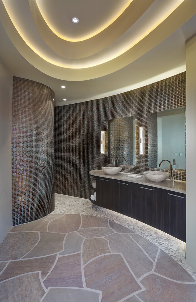 Пример оригинального дизайна: большая главная ванная комната в стиле фьюжн с плоскими фасадами, темными деревянными фасадами, отдельно стоящей ванной, душем в нише, унитазом-моноблоком, разноцветной плиткой, плиткой мозаикой, бежевыми стенами, полом из известняка, настольной раковиной, столешницей из известняка, коричневым полом и открытым душем