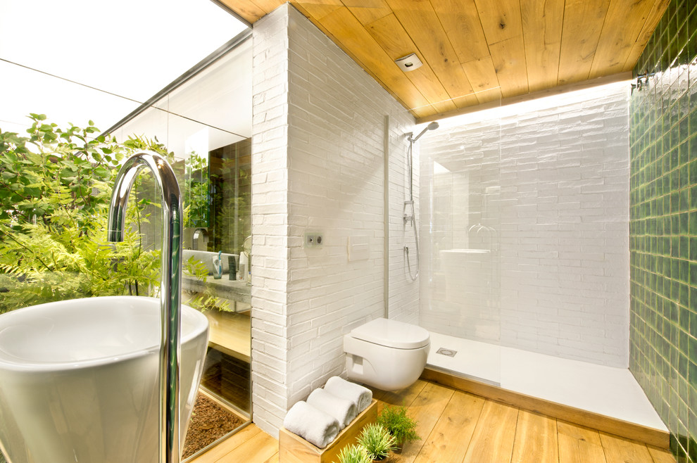Exemple d'une salle de bain exotique de taille moyenne avec WC suspendus, un mur multicolore, un sol en bois brun et un lavabo de ferme.