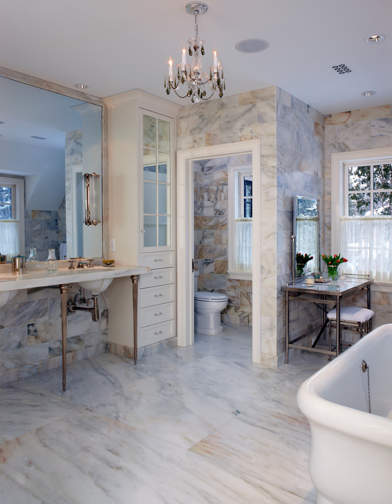 Aménagement d'une grande salle de bain principale craftsman avec un lavabo encastré, une baignoire indépendante, WC à poser, un placard avec porte à panneau encastré, des portes de placard blanches, un plan de toilette en marbre, un carrelage blanc, des dalles de pierre, un mur blanc et un sol en marbre.