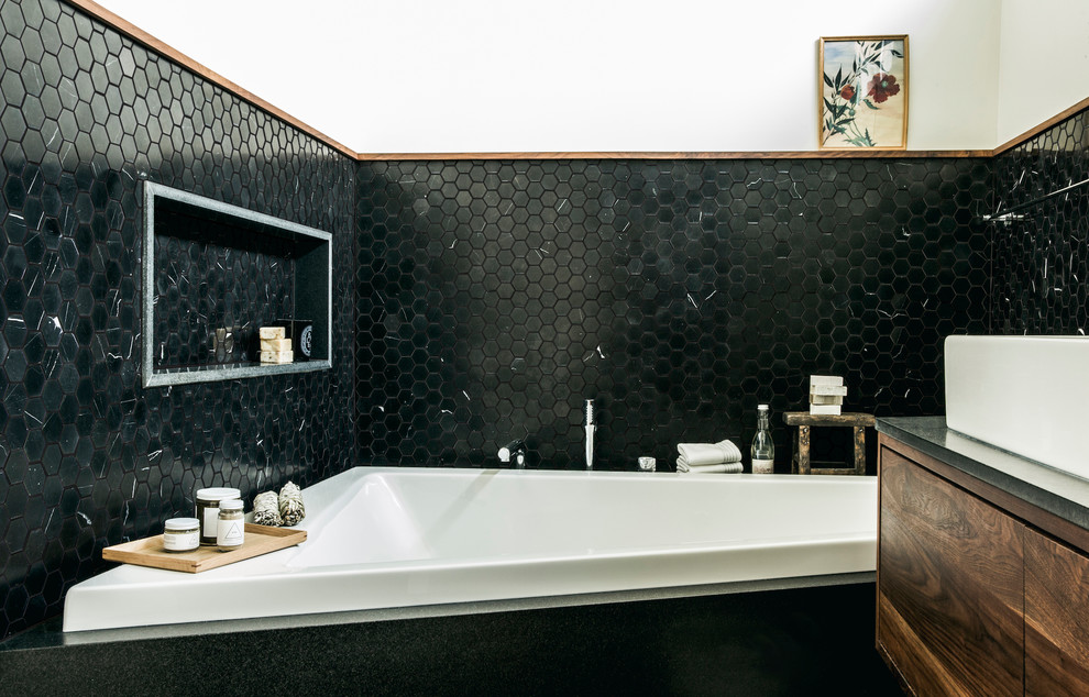Aménagement d'une salle de bain principale contemporaine en bois brun de taille moyenne avec un placard à porte plane, une baignoire en alcôve, un espace douche bain, un carrelage noir, mosaïque, un mur blanc, un sol en carrelage de terre cuite, une grande vasque, un plan de toilette en granite, un sol noir, une cabine de douche à porte battante, un plan de toilette noir, un banc de douche et meuble double vasque.