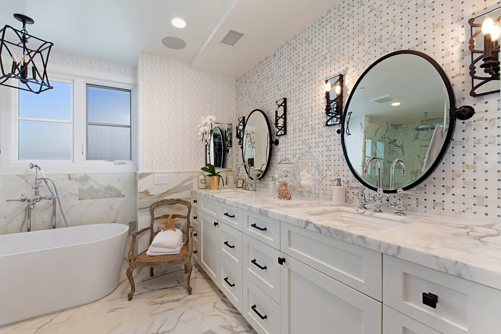 Inspiration for a coastal bathroom in Orange County with shaker cabinets, white cabinets, a freestanding bath, white tiles, mosaic tiles, white walls and a submerged sink.
