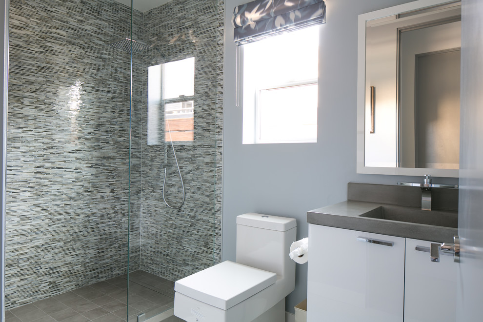 На фото: ванная комната среднего размера в современном стиле с плоскими фасадами, белыми фасадами, угловым душем, унитазом-моноблоком, разноцветной плиткой, плиткой мозаикой, серыми стенами, душевой кабиной, монолитной раковиной и открытым душем