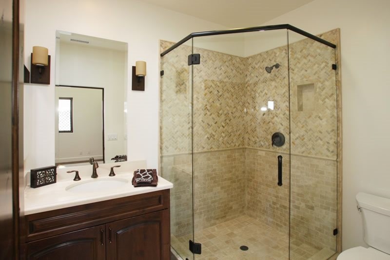 Exempel på ett stort medelhavsstil badrum med dusch, med luckor med upphöjd panel, skåp i mörkt trä, en dusch i en alkov, en toalettstol med separat cisternkåpa, flerfärgad kakel, stenkakel, vita väggar, ett undermonterad handfat och bänkskiva i akrylsten