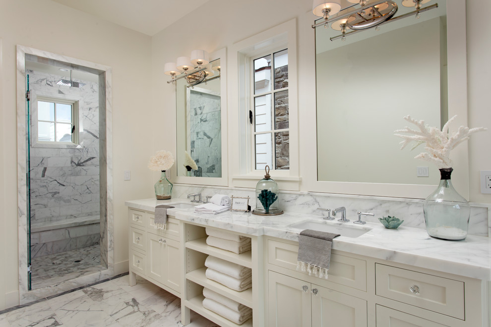 Inspiration for a large beach style ensuite bathroom in Orange County with shaker cabinets, white cabinets, a freestanding bath, an alcove shower, a one-piece toilet, white walls, a built-in sink and marble worktops.
