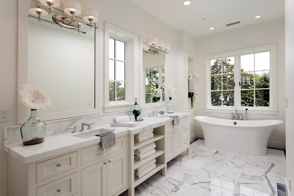 Ejemplo de cuarto de baño principal clásico renovado grande con armarios estilo shaker, puertas de armario blancas, bañera exenta, paredes blancas, encimera de mármol y lavabo bajoencimera