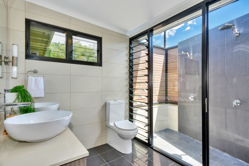 Пример оригинального дизайна: ванная комната в современном стиле с душем в нише, раздельным унитазом, бежевыми стенами, бетонным полом, настольной раковиной, серым полом и душем с раздвижными дверями