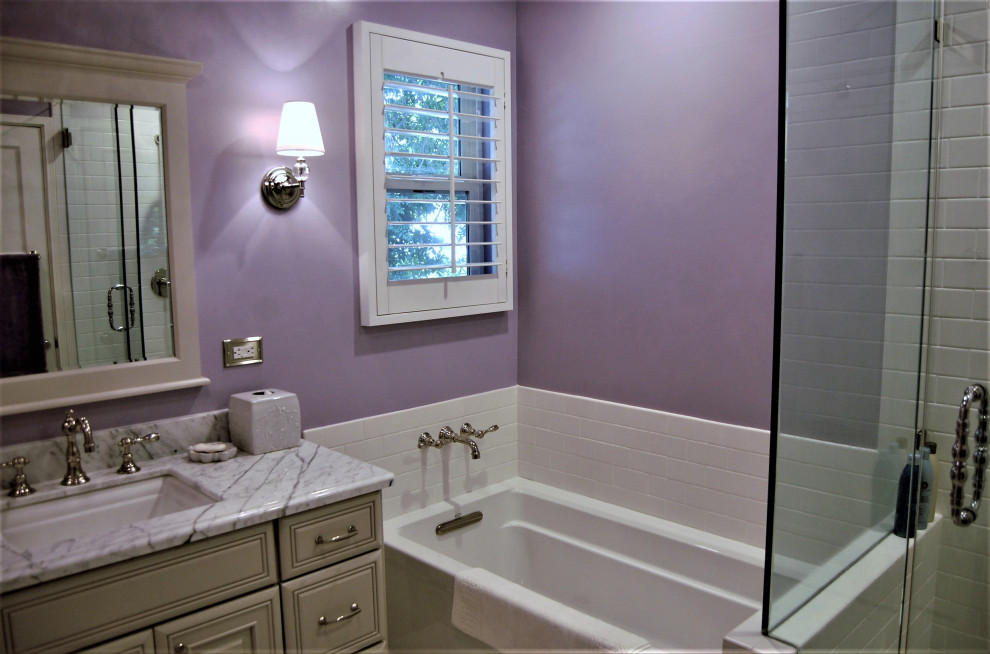 Стильный дизайн: маленькая главная ванная комната в классическом стиле с фасадами с выступающей филенкой, бежевыми фасадами, ванной в нише, угловым душем, раздельным унитазом, белой плиткой, плиткой кабанчик, фиолетовыми стенами, полом из керамогранита, врезной раковиной, мраморной столешницей, душем с распашными дверями, разноцветной столешницей, тумбой под одну раковину, встроенной тумбой и белым полом для на участке и в саду - последний тренд