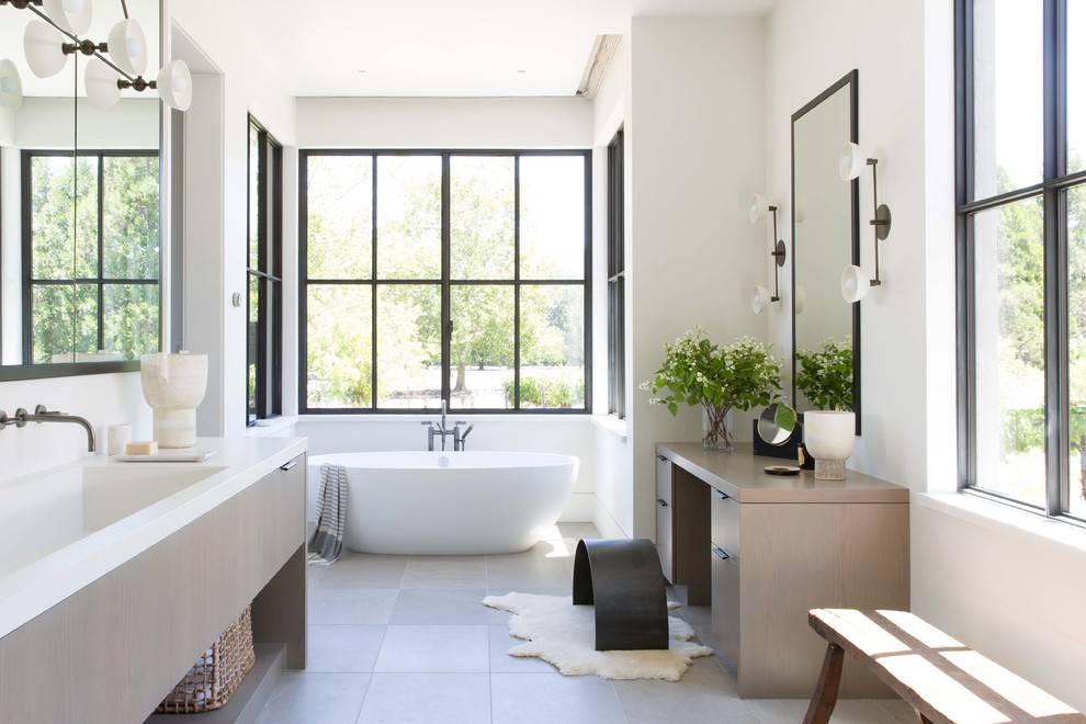 Landhaus Badezimmer En Suite mit flächenbündigen Schrankfronten, hellen Holzschränken, freistehender Badewanne, weißer Wandfarbe, integriertem Waschbecken, grauem Boden und weißer Waschtischplatte in San Francisco