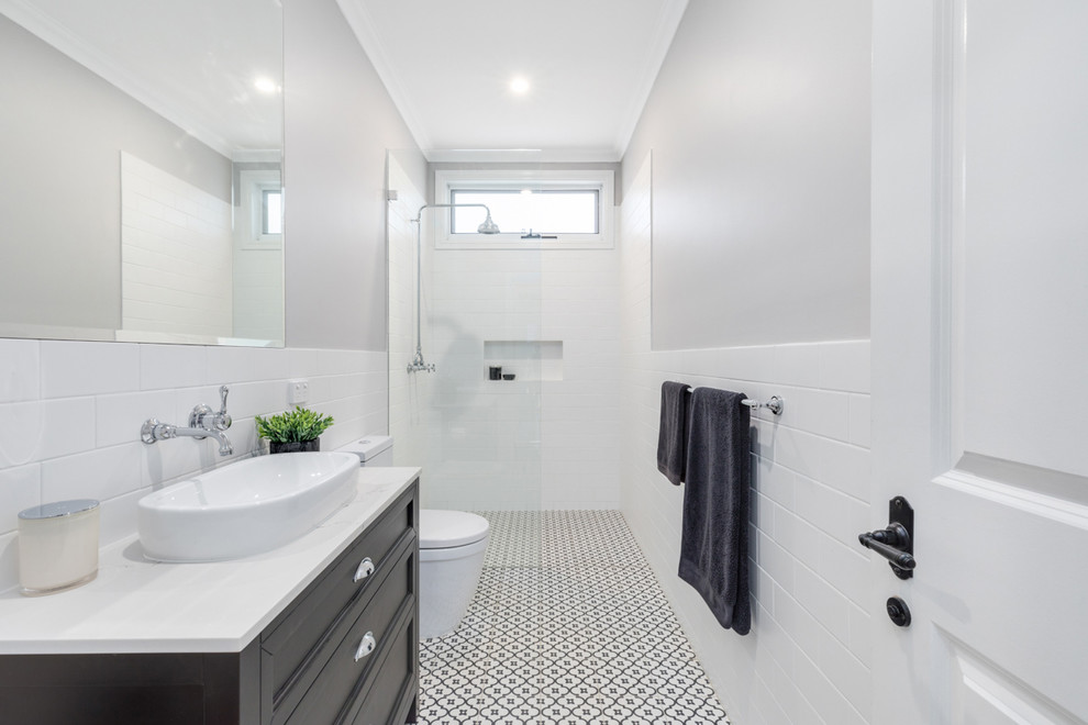 Imagen de cuarto de baño tradicional renovado con armarios estilo shaker, puertas de armario negras, lavabo sobreencimera, encimera de mármol, paredes grises, suelo de azulejos de cemento, suelo negro y hornacina
