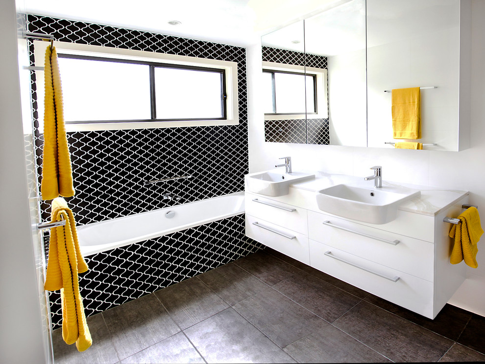 シドニーにあるコンテンポラリースタイルのおしゃれな浴室 (フラットパネル扉のキャビネット、白いキャビネット、アルコーブ型浴槽、シャワー付き浴槽	、黒いタイル、モノトーンのタイル、白い壁) の写真